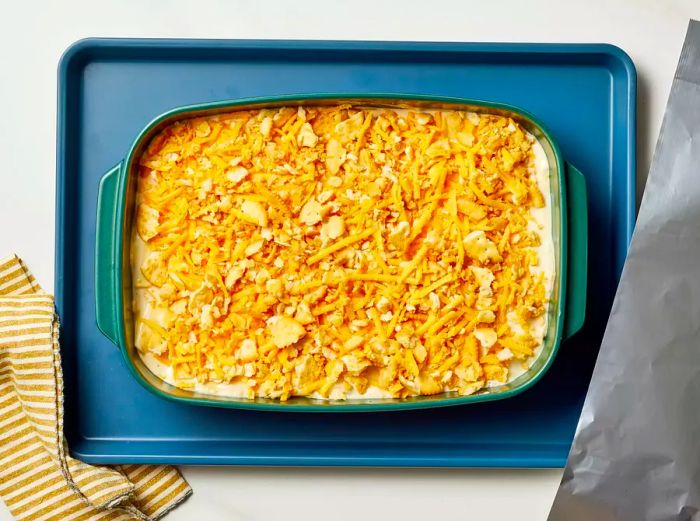 Unbaked Million Dollar Potato Casserole in a baking dish, resting on a baking sheet.