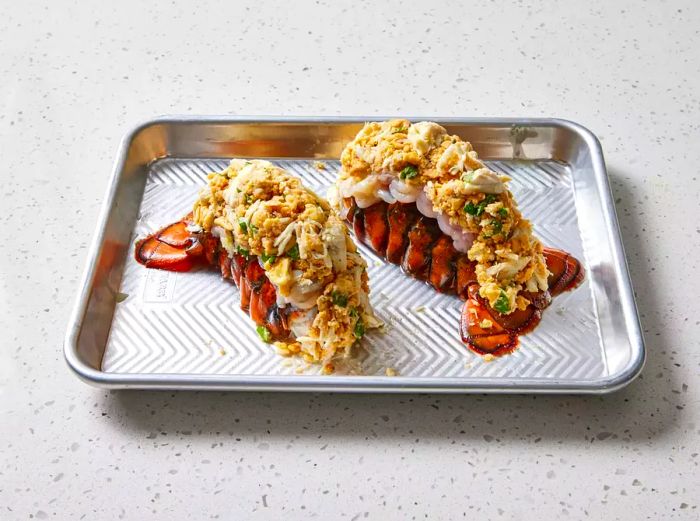 Crab-stuffed lobster tails arranged on a baking sheet, ready to bake