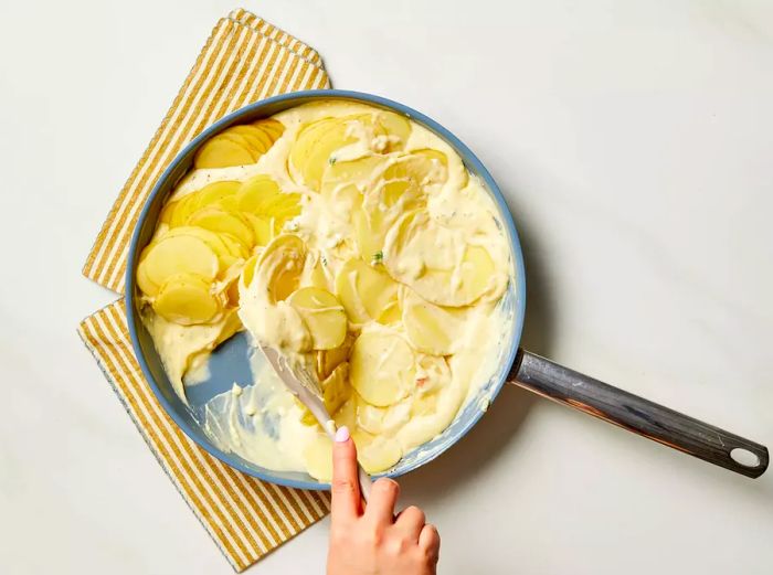 Mixing the potatoes and creamy chicken soup mixture in a pan