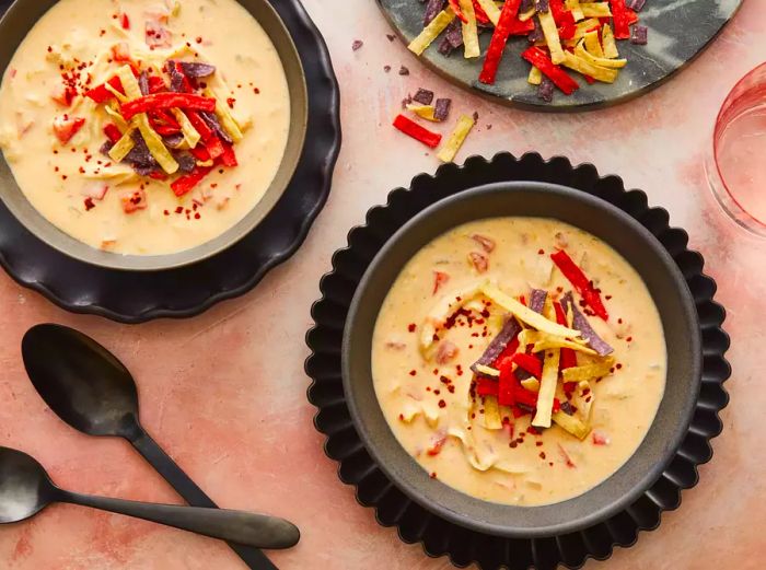 A close-up of two large bowls of creamy chicken taco soup, garnished with crispy tortilla strips