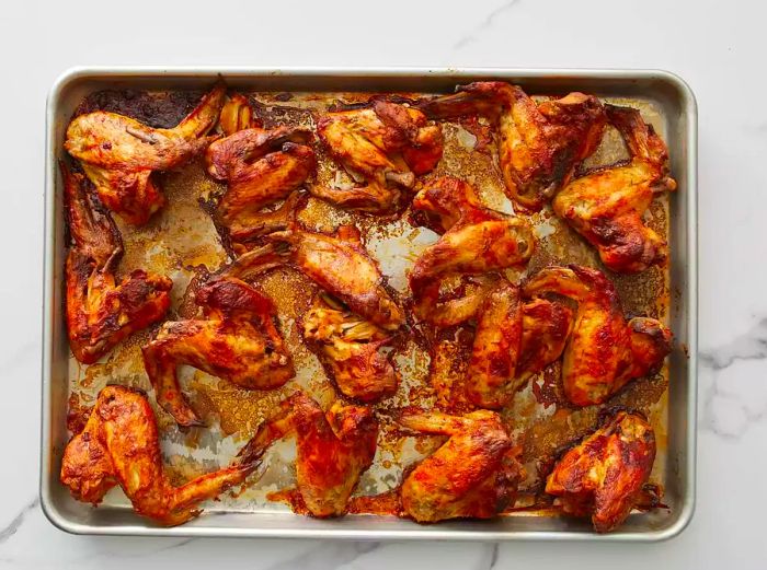 An overhead view of chicken wings neatly arranged on a baking sheet