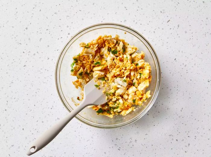 Crab mixture in a glass bowl with a spatula, ready to be used