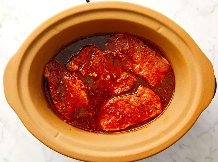 top view of pork chops and marinade in slow cooker