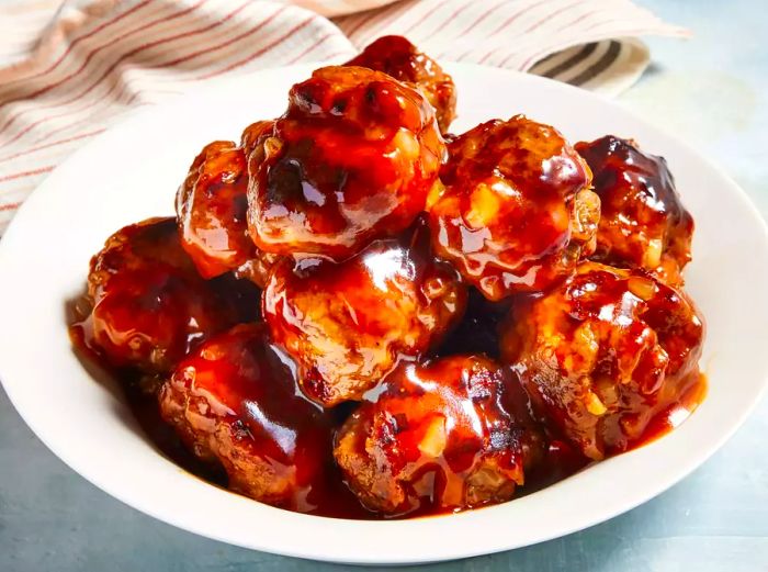 A top-down view of a plate filled with juicy, saucy sweet and sour meatballs.