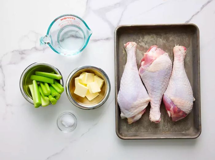 A bird's-eye view of the ingredients for turkey legs, arranged in various bowls and pans.