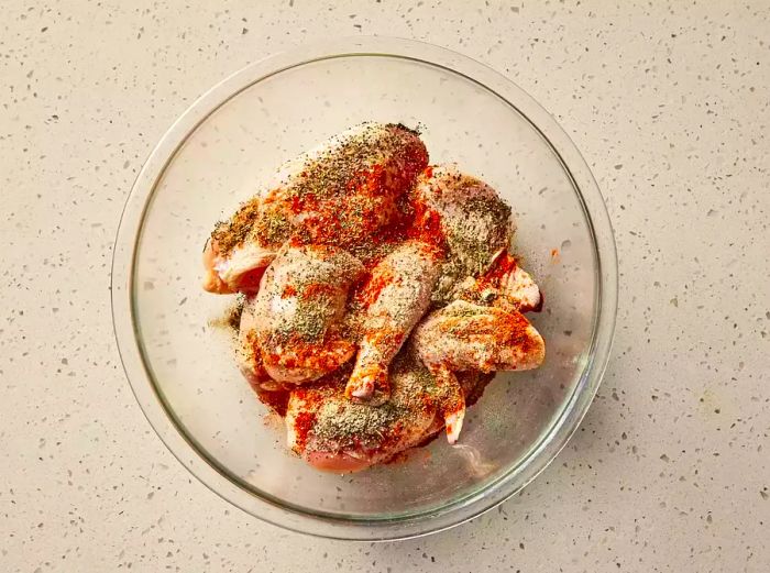 chicken pieces coated with seasonings in a mixing bowl