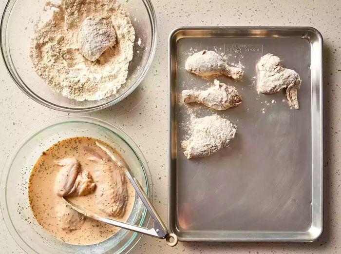 chicken coated in flour and set aside on a tray