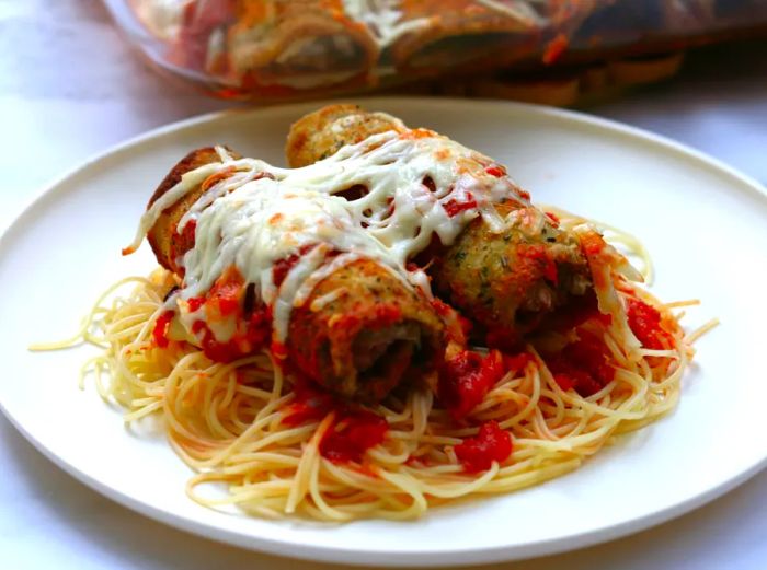 Eggplant rollatini served on a bed of pasta.