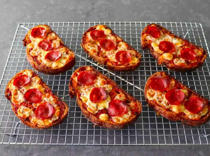 Bread and butter pizza topped with melted mozzarella and pepperoni slices resting on a wire rack.