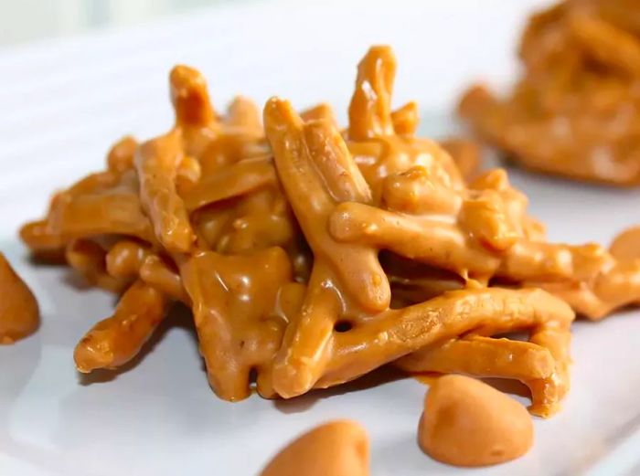 A close-up view of a single peanut butter haystack with a few peanut butter chips placed in front of it, captured at eye level.