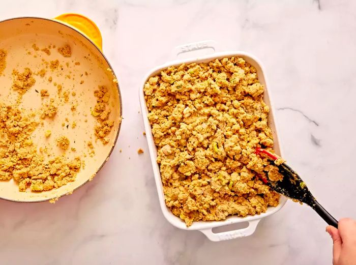 A top-down shot of the oyster stuffing being added to a baking dish.