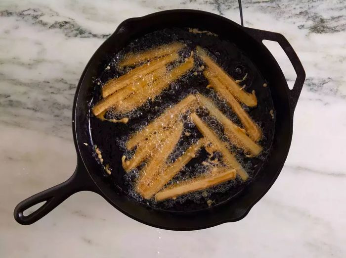 Aerial shot of fries frying in oil in a skillet.