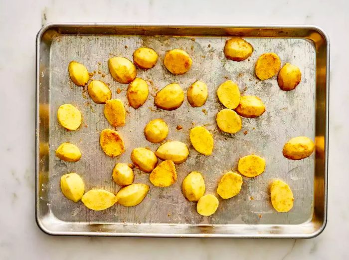 Potatoes coated in oil, seasonings, and cornstarch, ready for roasting.