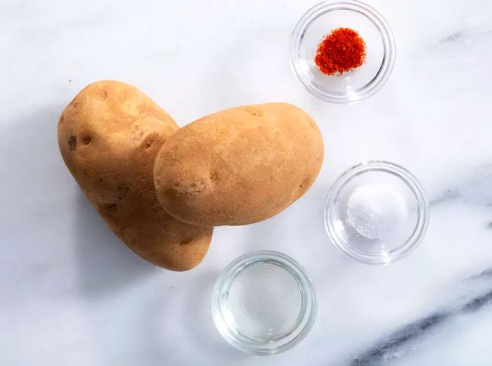 A high-angle view of the ingredients laid out for making French fries, including whole potatoes.