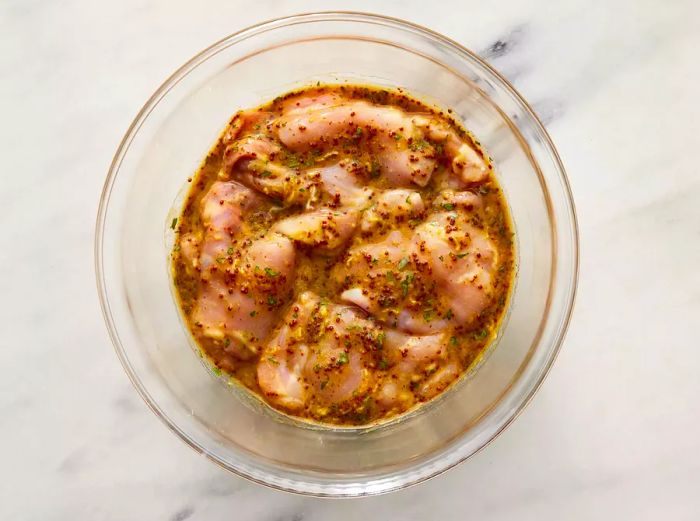 Aerial view of chicken soaking in a flavorful mustard and spice marinade.