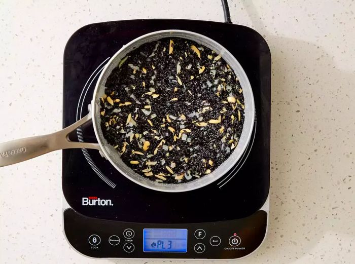 Black rice and nuts cooking together in a pot on a burner