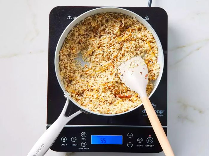 A pot of soaked basmati rice with caramelized onions and toasted spices