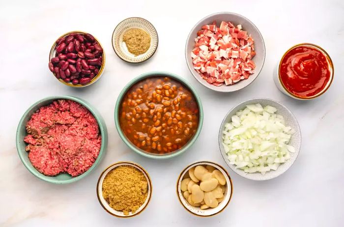 Various small bowls filled with ingredients for making slow cooker cowboy beans.