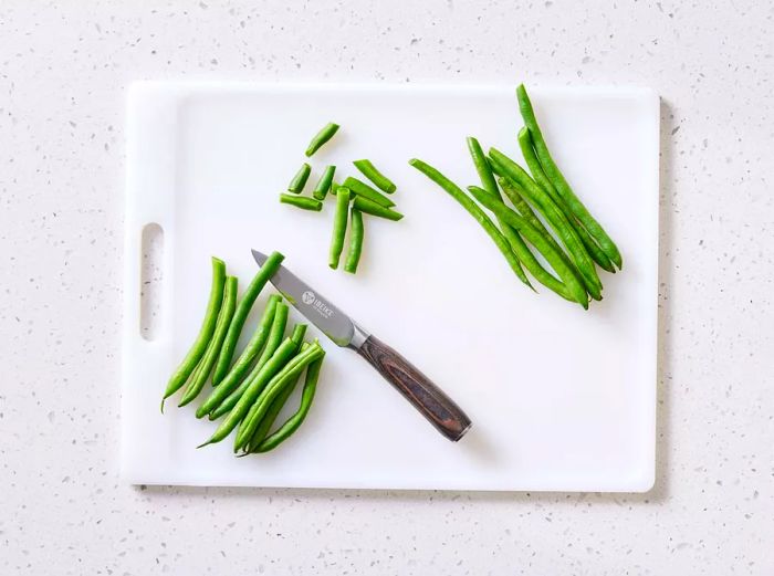 A cutting board with freshly trimmed green beans