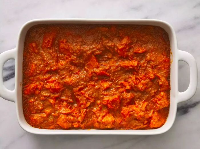 A baking dish filled with mashed sweet potatoes in a rich marshmallow-brown sugar sauce