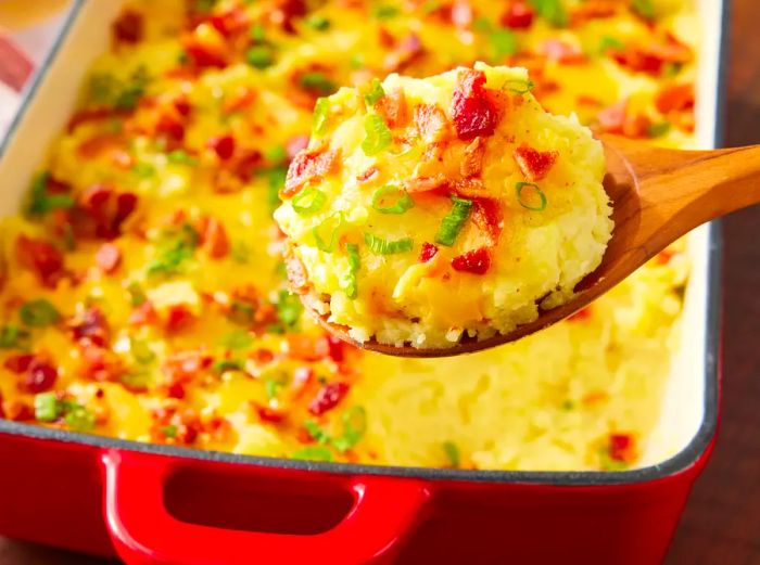 A spoonful of Easy Loaded Baked Potato Casserole, with more casserole visible in the background