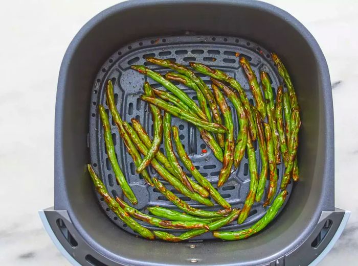 A top-down view of crispy green beans inside an air fryer