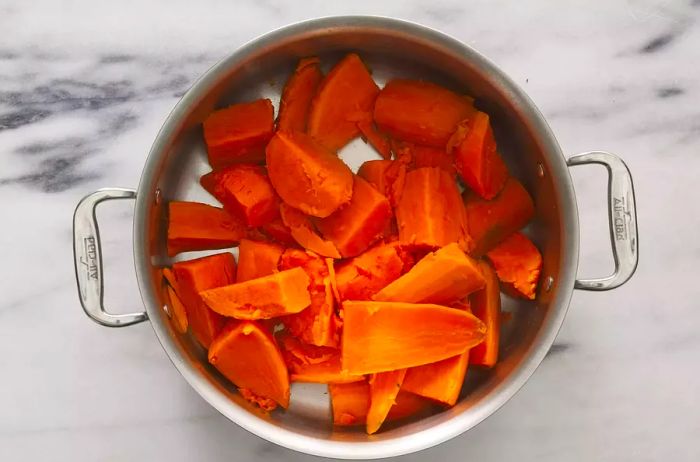 A large pot filled with quartered, boiled, and peeled sweet potatoes