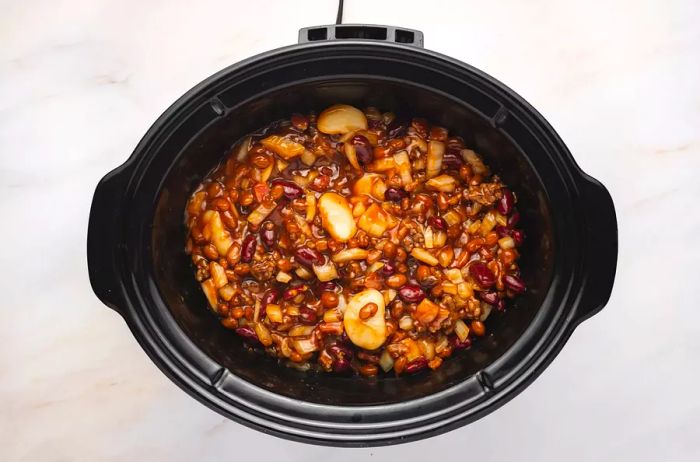 Beans cooking in a black crockpot.