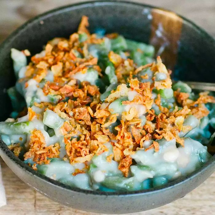 A close-up shot of slow-cooked green beans topped with crunchy fried onions.