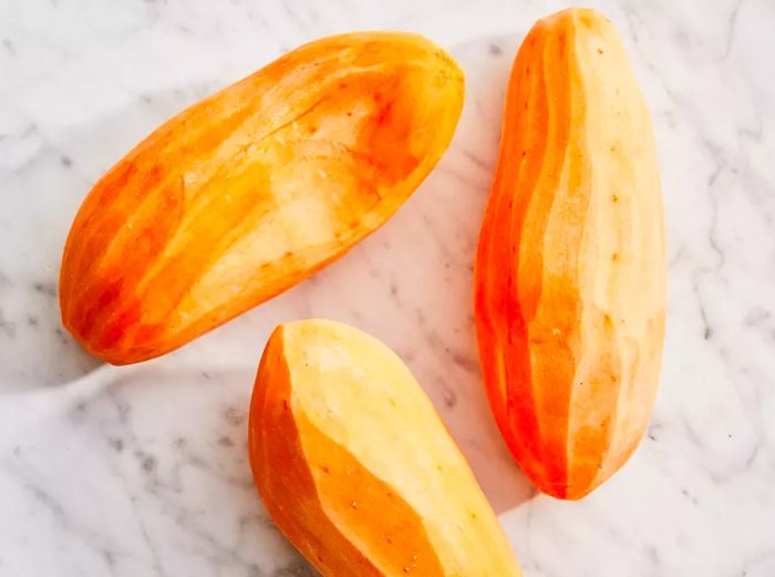 A top-down shot of three peeled sweet potatoes.