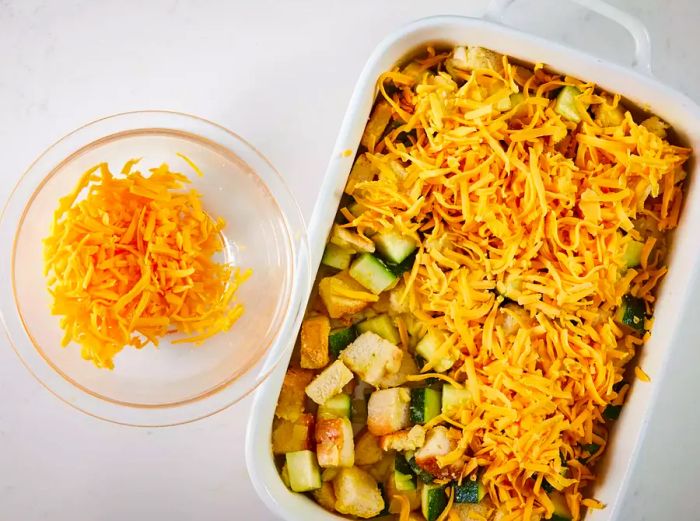 A top-down view of zucchini casserole garnished with shredded cheese in a baking dish