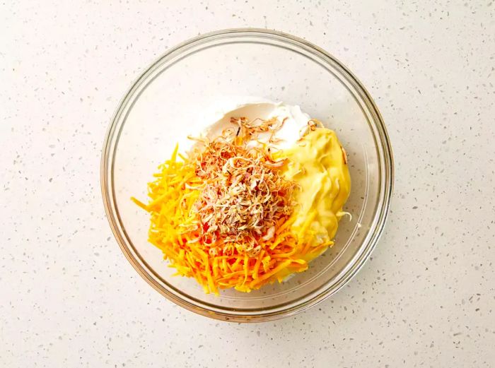 A bowl of sour cream, condensed soup, cheddar cheese, and crispy onions.