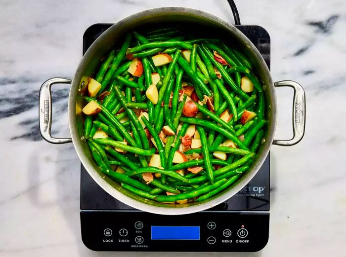 A large pot of tender Southern-style green beans with potatoes and crispy bacon