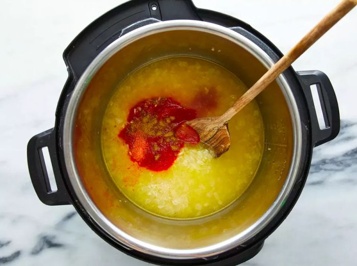 Tomato sauce, salt, cumin, and cayenne pepper added to the pressure cooker and mixed in.