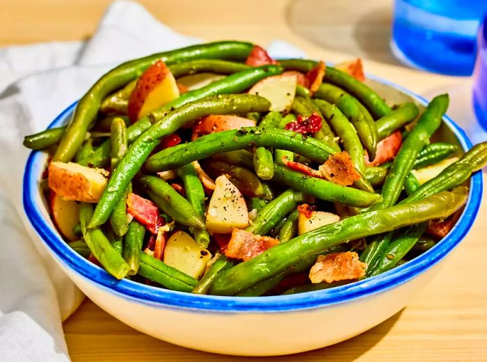 A serving dish filled with Southern-style green beans, potatoes, and bacon