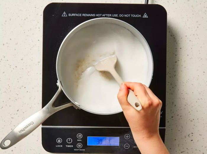 Stirring rice with coconut milk in a pot over a burner