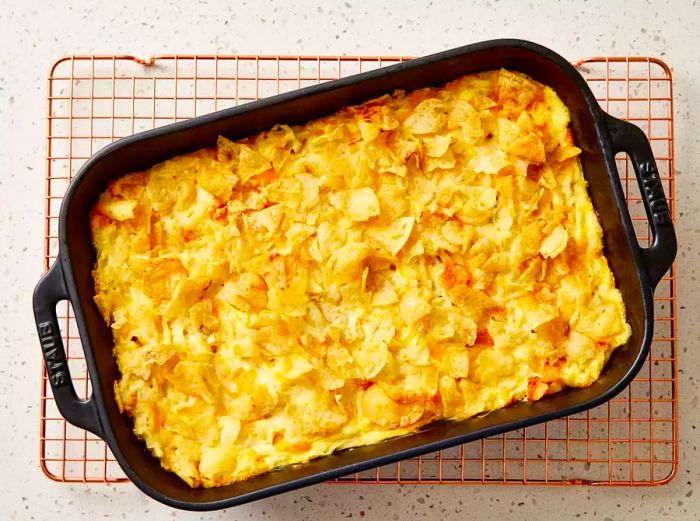 A baking dish of classic funeral potatoes resting on a wire cooling rack.