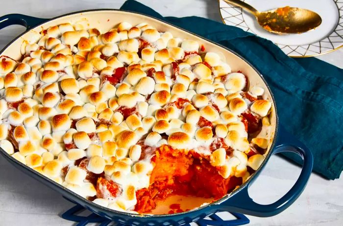 Candied yams served in a navy blue casserole dish with a slice removed.