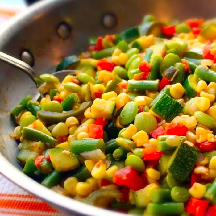 Close-up of a vegetable succotash with zucchini, peppers, corn, lima beans, and green beans in a skillet