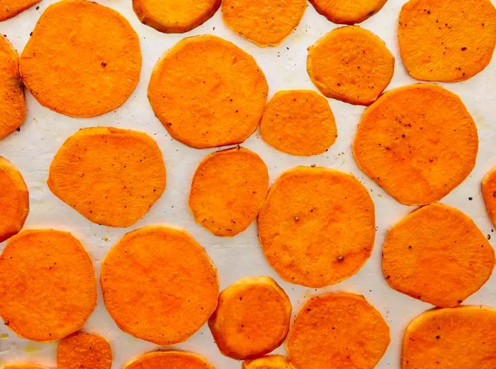 A close-up view of a baking sheet filled with roasted yam slices.