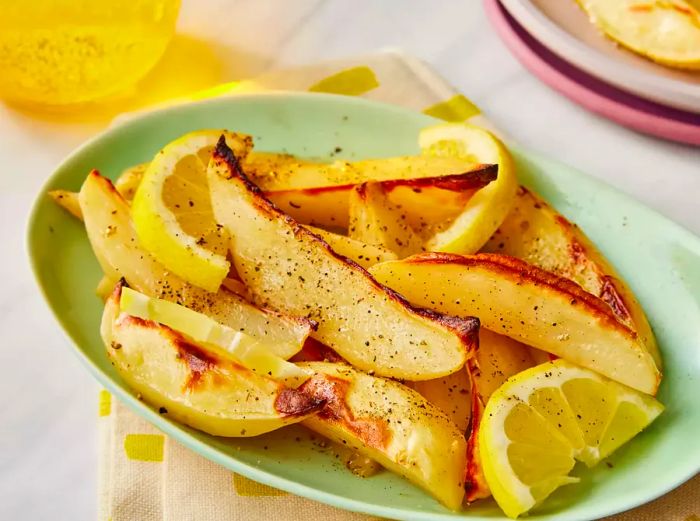 A close-up shot of an oval platter filled with delicious Greek-style lemon roasted potatoes.