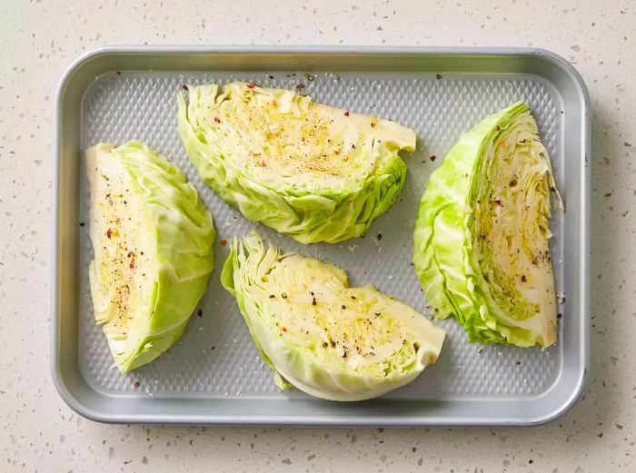 Seasoned cabbage wedges laid out on a baking tray