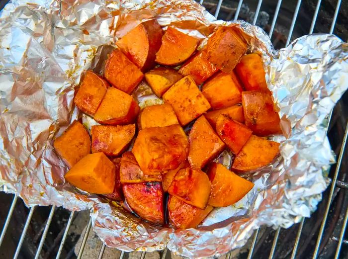 Sweet potatoes grilling in foil packets on the barbecue.