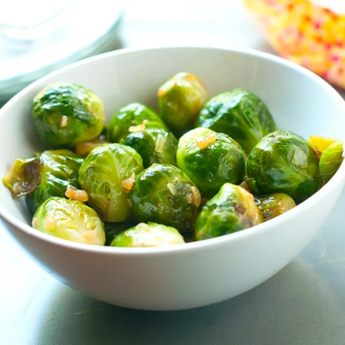 A close-up shot of roasted Brussels sprouts served in a white bowl