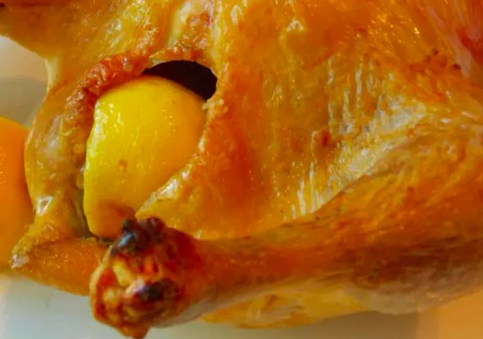 Close-up of a roast chicken with a lemon half in the cavity