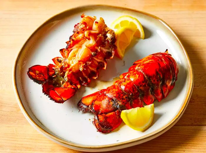 A close-up shot of two grilled rock lobsters on a plate.