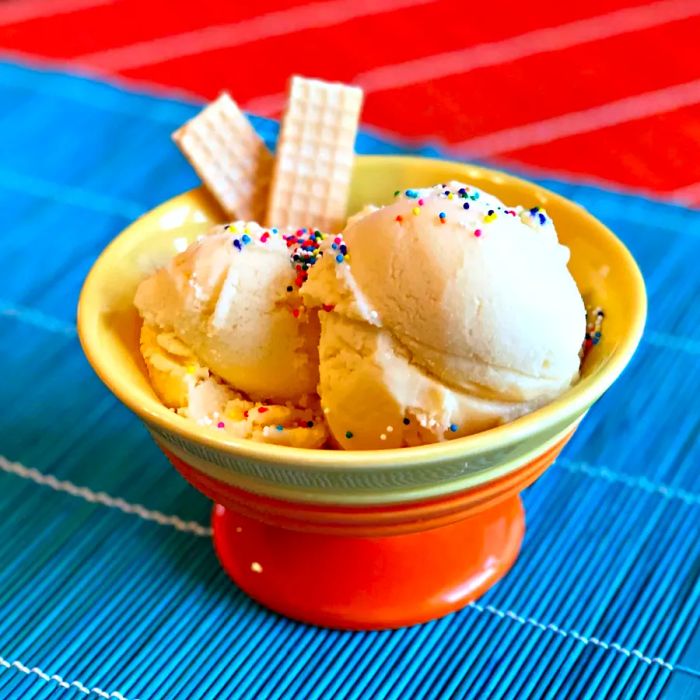 A bowl of vanilla ice cream topped with sprinkles and wafers