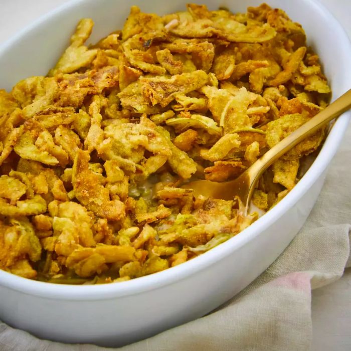 Green bean casserole with a golden spoon serving a portion