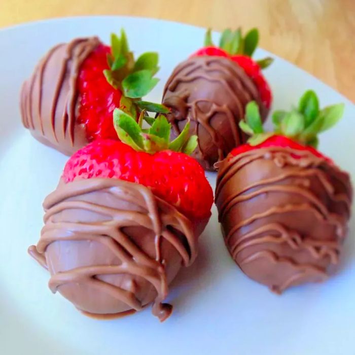 Four homemade chocolate-covered strawberries.