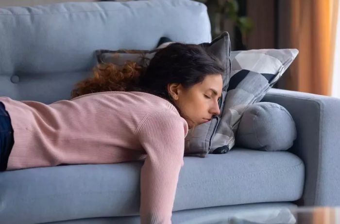 Exhausted young woman resting on the couch at home